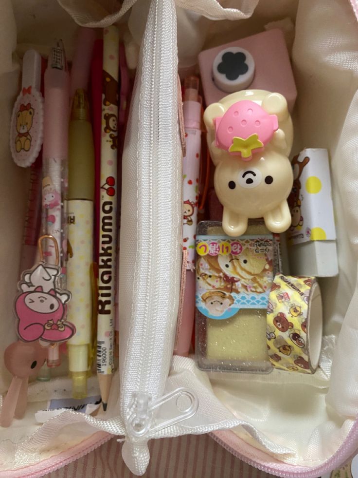 the contents of a pink and white bag are neatly packed with pens, pencils, and other items