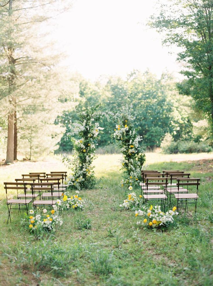 an outdoor ceremony set up with wooden chairs and flowers