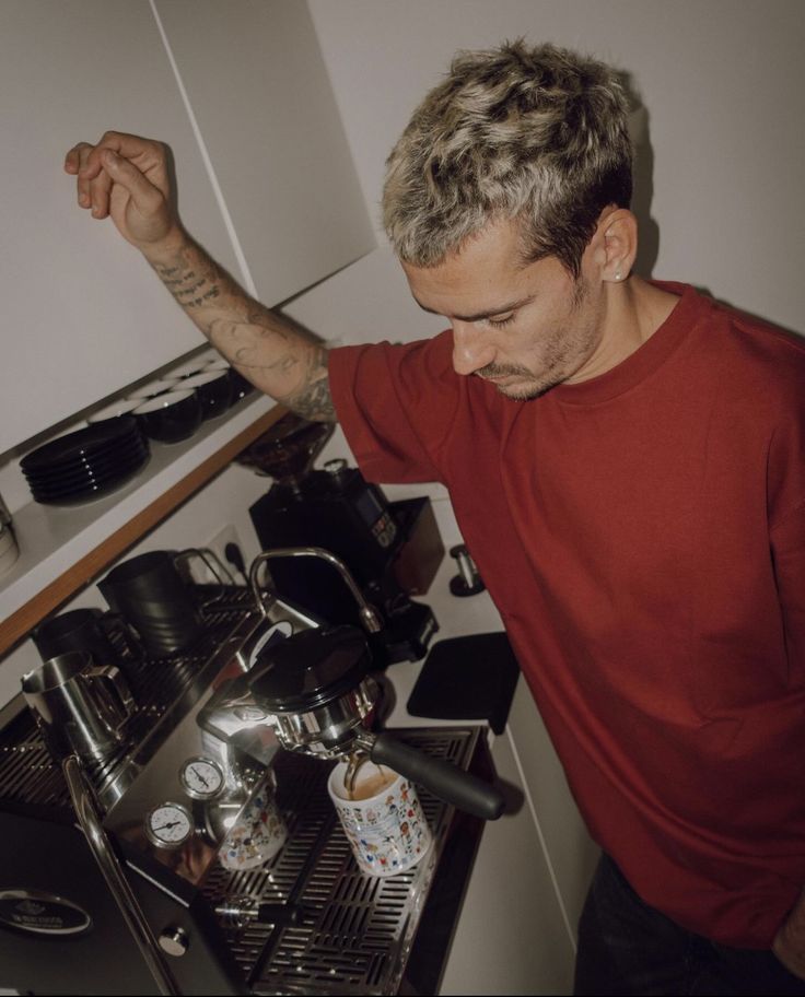 a man in a red t - shirt is working on an espresso machine