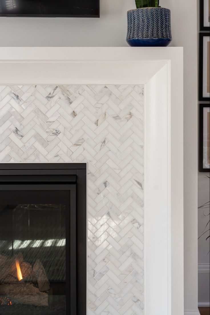 a white fireplace with a black fire place in the corner and pictures on the wall