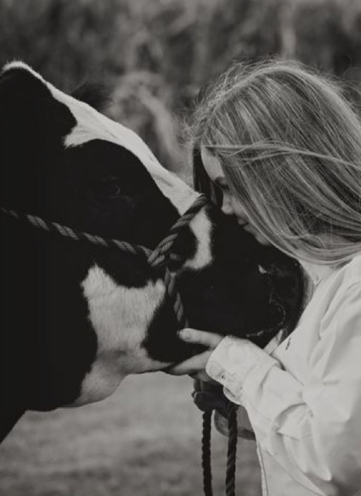 a black and white photo of a woman kissing a cow