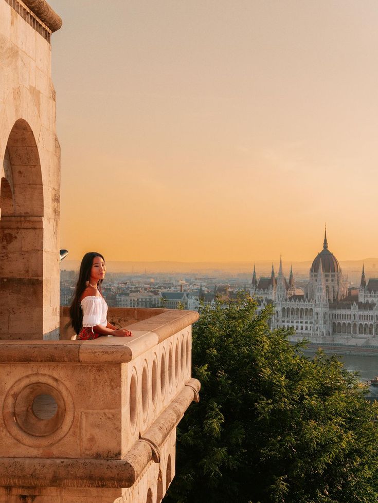 a woman sitting on top of a balcony next to a tree