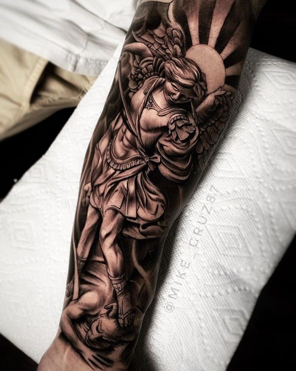 a man's arm with an angel and sun tattoo design on the left forearm