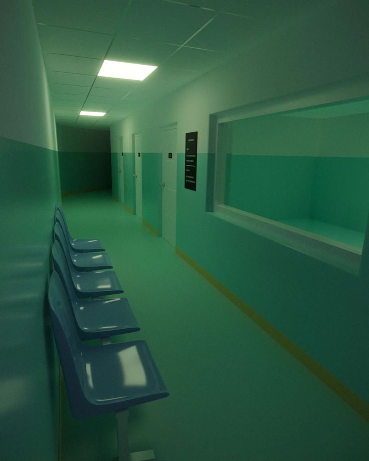 an empty hallway with blue benches and green walls