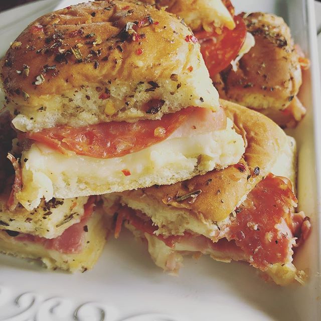 a close up of a plate of food with meat and cheese on bread buns