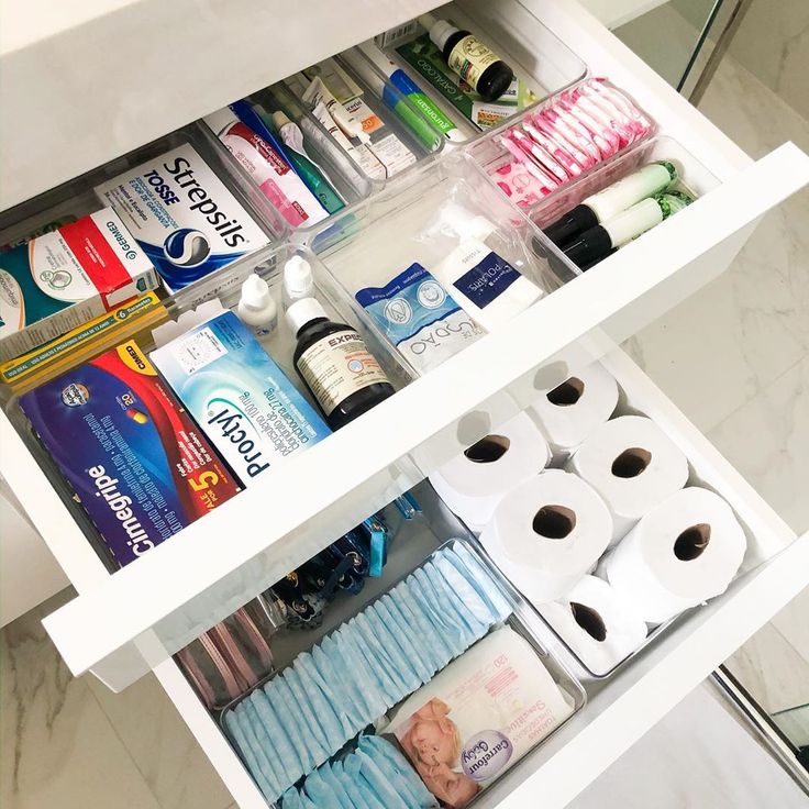 an organized bathroom drawer with toiletries and rolls of toilet paper on the bottom shelf