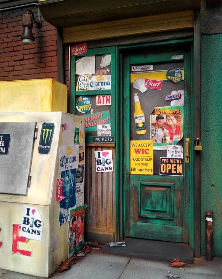 an old refrigerator sitting outside of a building with posters on the front door and windows