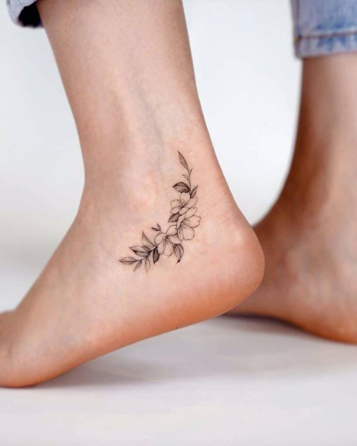 a woman's foot with a small flower tattoo on her left side calfocks