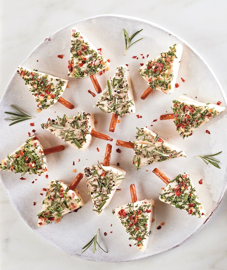 a white plate topped with cut up carrots covered in cheese and herbs on top of a marble table