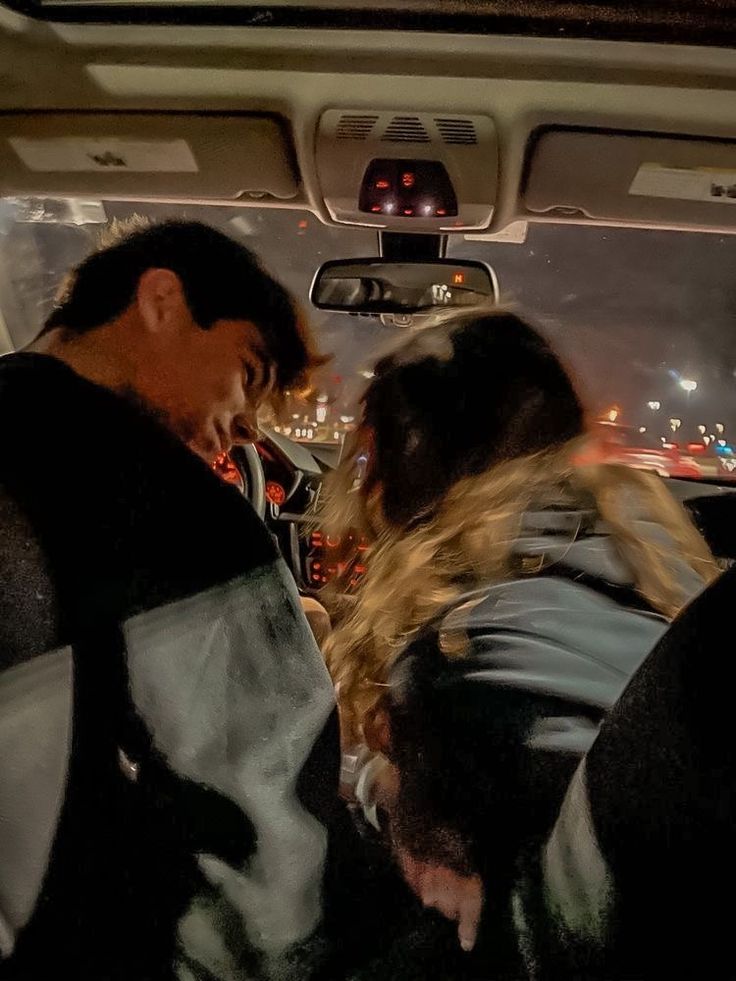 two people sitting in the back seat of a car