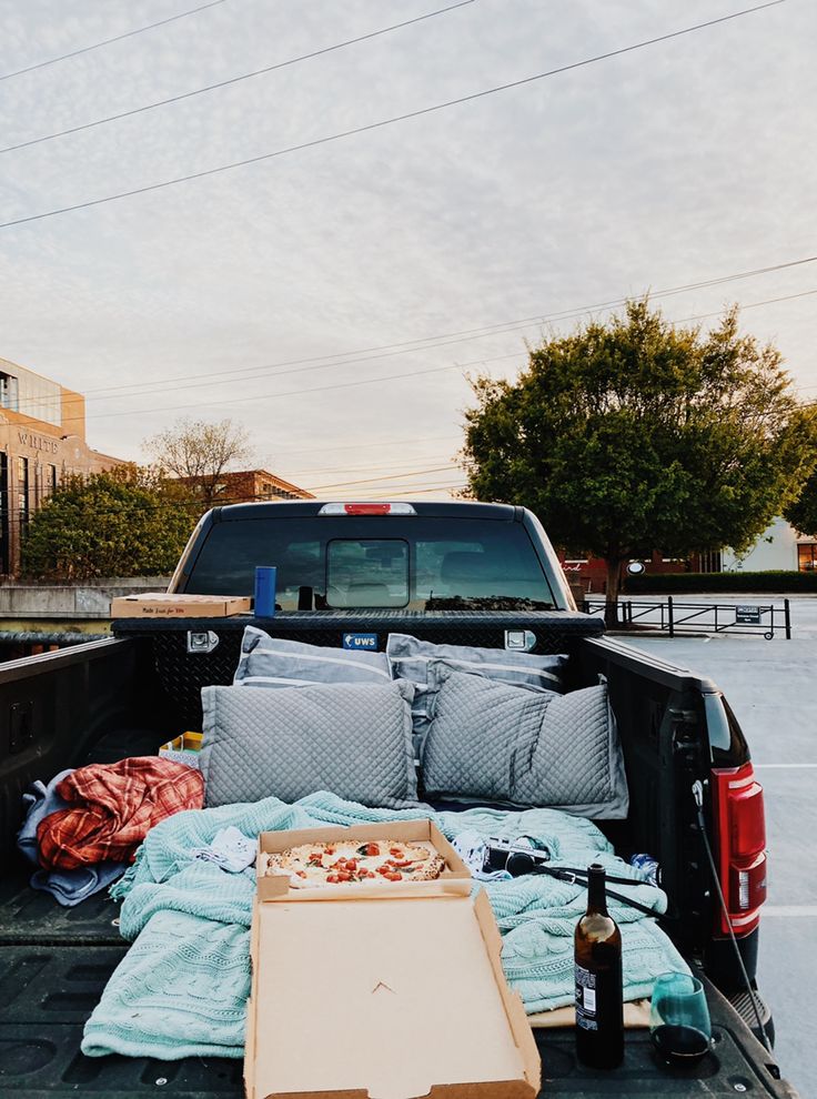 the back of a pickup truck loaded with blankets and pizza on it's bed