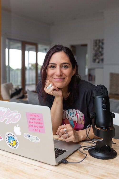 a woman sitting at a table in front of a laptop with stickers on it