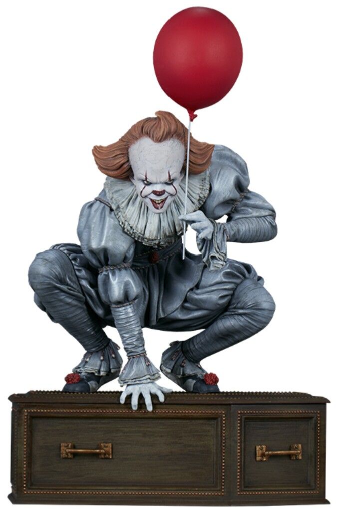 a statue of a clown holding a red balloon on top of a chest with two drawers