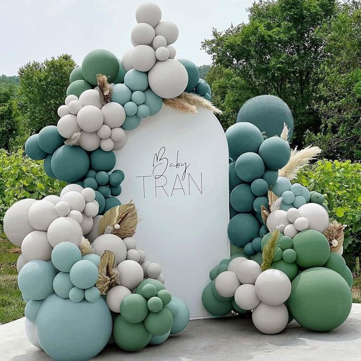 an arch made out of balloons and grass with the words be my train written on it