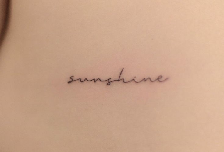 the word sunshine written in cursive handwriting on the back of a woman's stomach