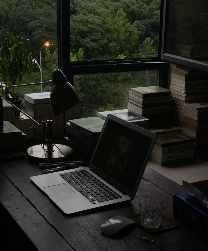 an open laptop computer sitting on top of a wooden desk in front of a window