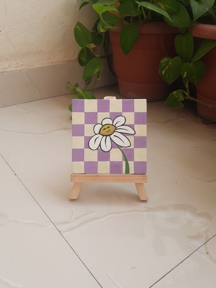 a small wooden easel with a flower painted on it