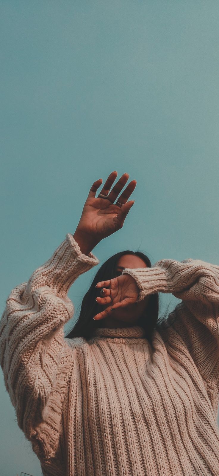 a woman in a white sweater is holding her hands up to the side with both hands