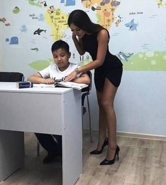 a woman standing next to a boy at a desk