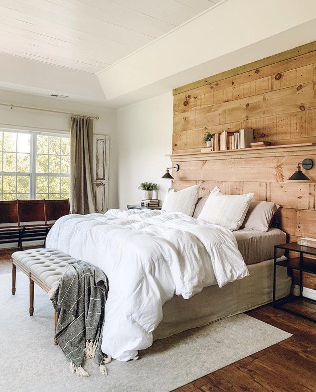 a large bed with white sheets and pillows on top of it in a bedroom next to a window