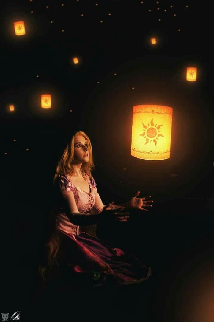 a woman is sitting in the dark with lanterns floating above her and looking up at the sky