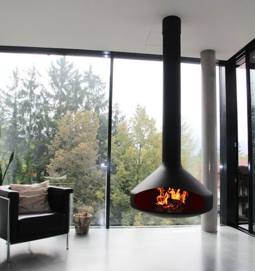 a living room with a fire place in the center and large glass windows on both sides