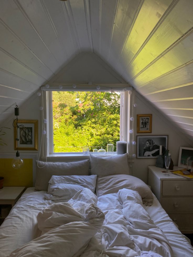 an unmade bed sitting under a window in a bedroom