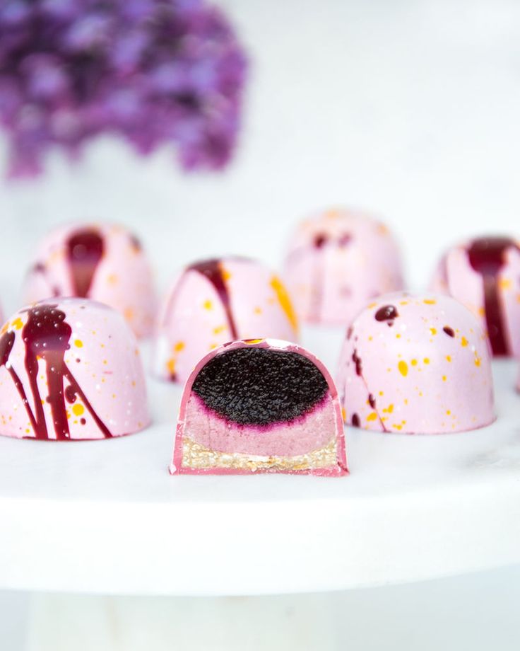 several pieces of cake sitting on top of a white plate with purple flowers in the background