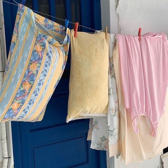 clothes hanging on the clothesline in front of a blue door with flowers and stripes