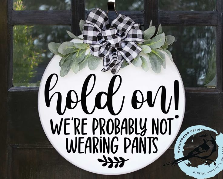 a door hanger that says hold on we're probably not wearing pants with a bow