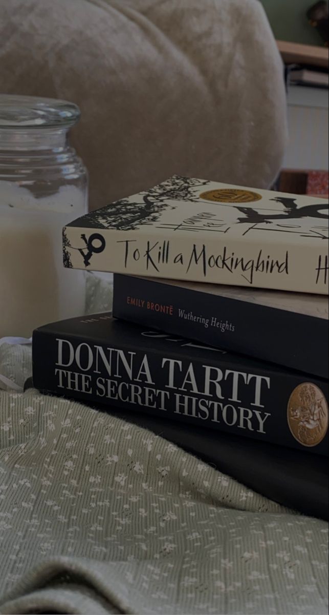 three books stacked on top of each other in front of a glass jar filled with milk