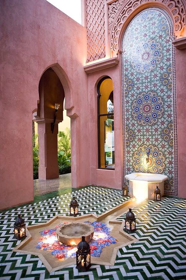 an elaborately decorated courtyard with lanterns and lights on the floor, in front of a pink wall