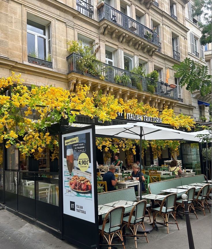 an outdoor restaurant with tables and umbrellas on the sidewalk in front of a building