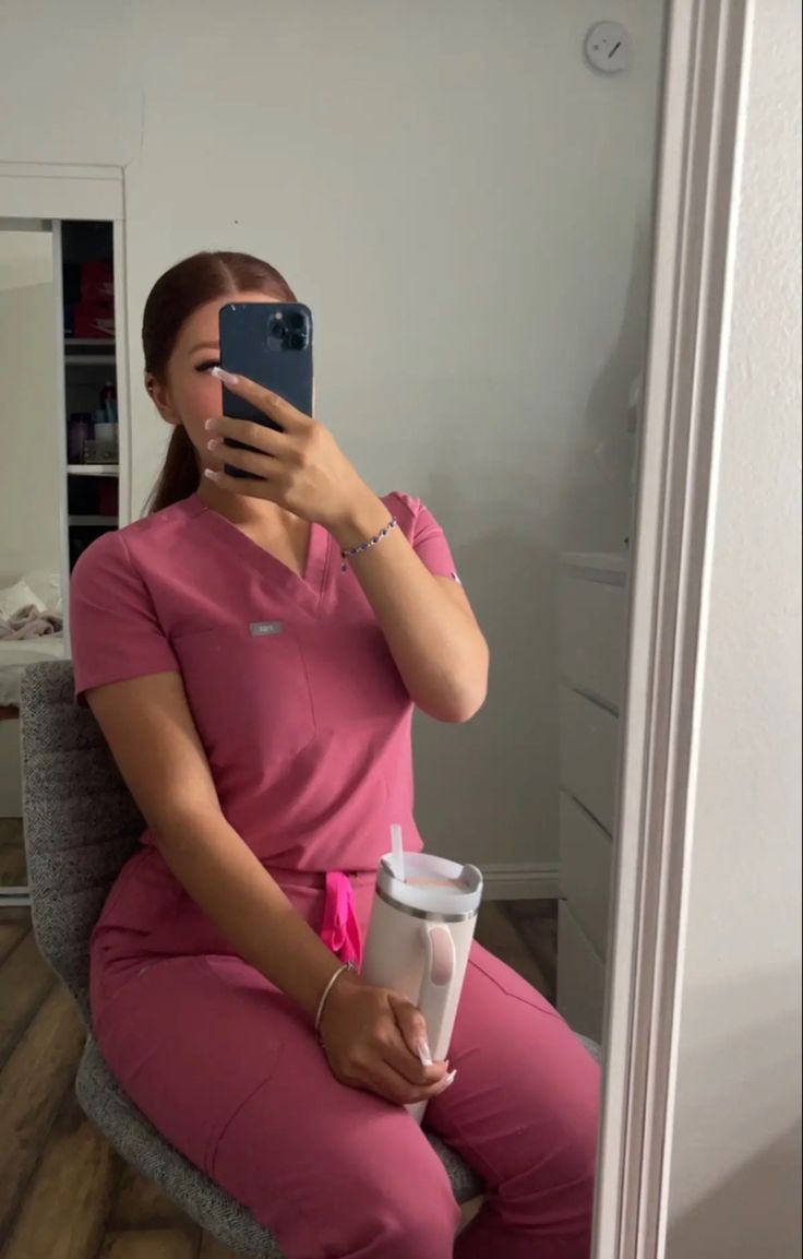 a woman sitting in a chair taking a selfie with her cell phone and holding a cup