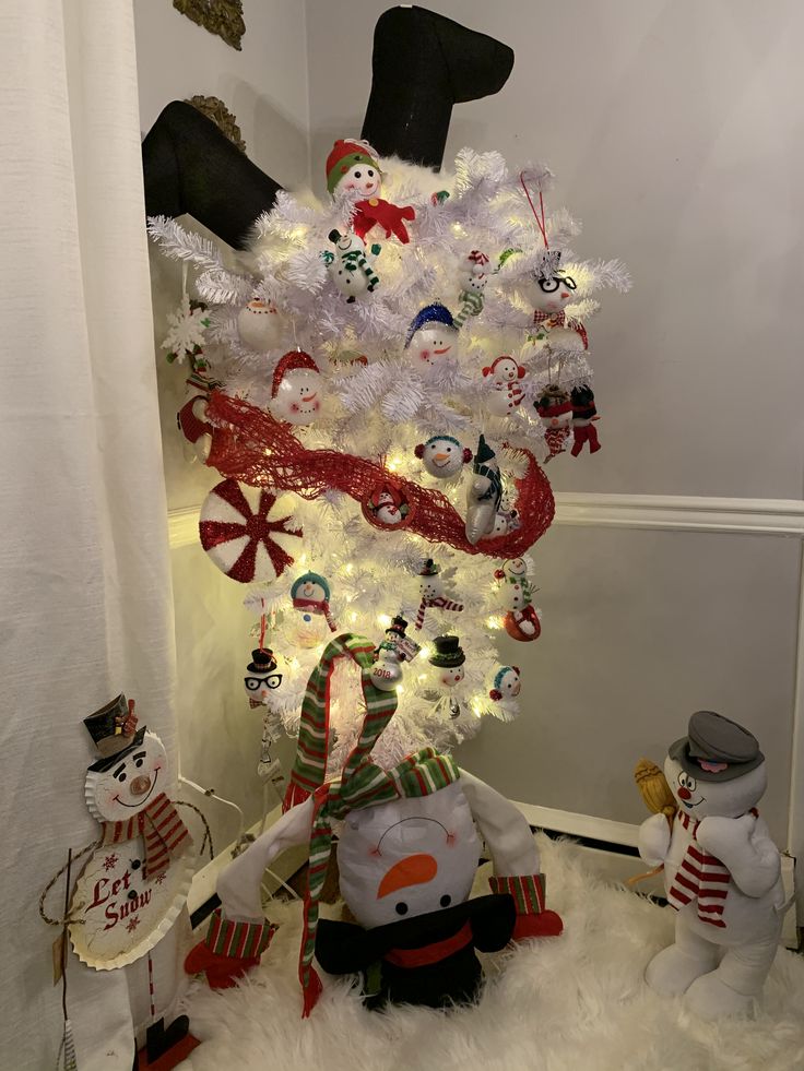 a white christmas tree decorated with snowmen and ornaments