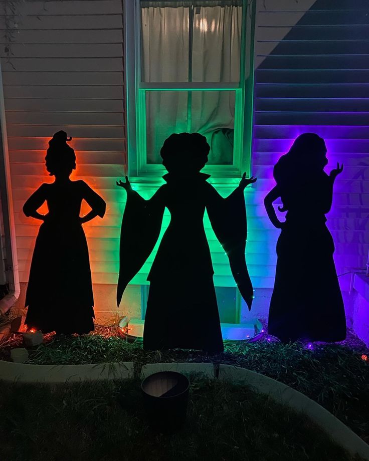 three silhouettes in front of a house at night