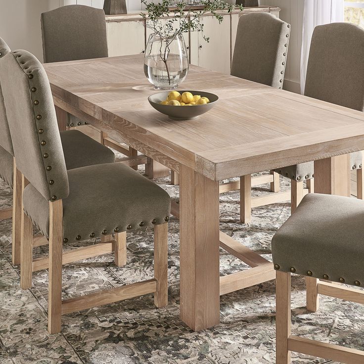 a dining room table with chairs and a bowl of lemons on the centerpiece