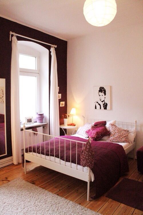 a bed room with a neatly made bed next to a window and a rug on the floor