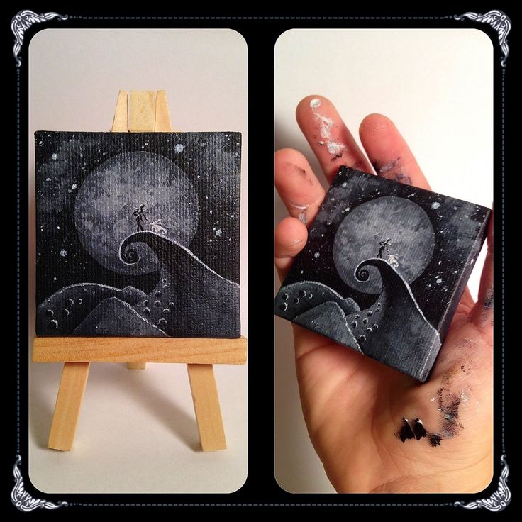 a hand holding up a small painting on an easel with the moon and stars painted on it