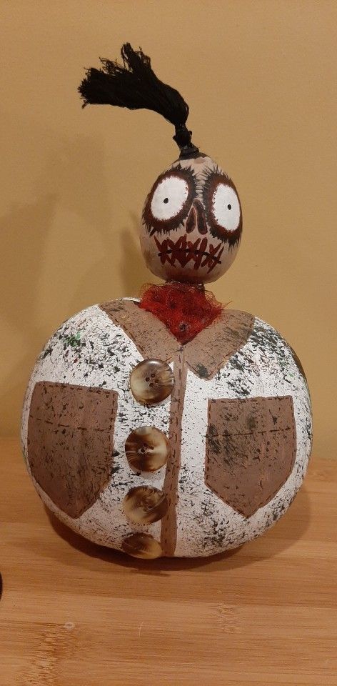 a rock with a face painted on it and hair sticking out of the top, sitting on a wooden table