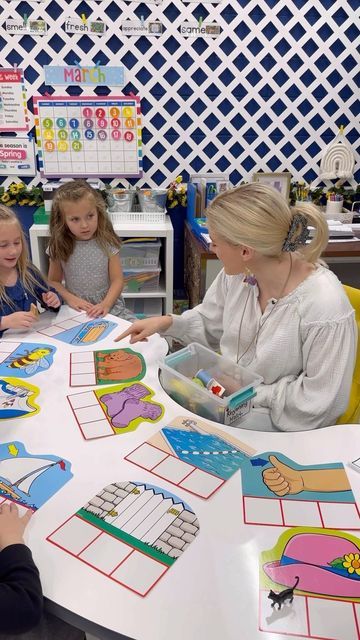 a group of children sitting around a table with paper cutouts on it and an adult standing next to them