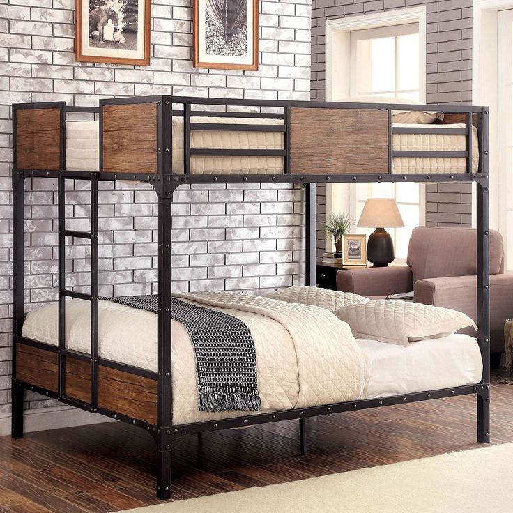 a metal bunk bed with wooden slats and white sheets in a living room next to a brick wall