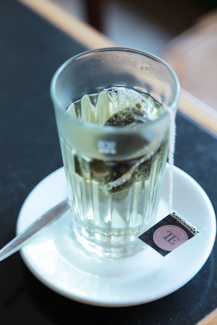 a glass filled with water sitting on top of a white plate