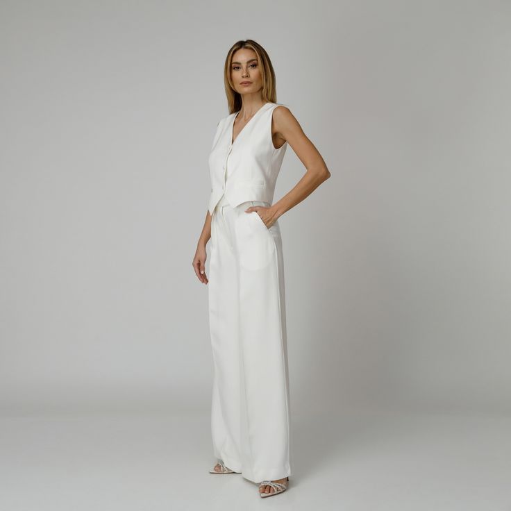 Introducing our Dove Silk Crepe Pants, a statement of luxurious comfort and timeless style. Tailored from white silk crepe with a wide-leg cut, they feature expertly placed darts that contour the waist and flatter the silhouette. The pressed crease detail offers a touch of refinement, elevating the overall look with understated polish. A concealed zipper and hook fastening in the front ensures a seamless finish, while the inclusion of pockets adds a practical yet chic element to the ensemble.  M Elegant Tailored White Wide Leg Pants, Elegant Tailored Wide Leg Pants For Summer, Elegant White Wide Leg Pants For Formal Occasions, Elegant White Wide Leg Pants, White Wide Leg Pants For Evening, Chic White Wide Leg Pants For Evening, Chic White Wide Leg Pants For Formal Occasions, Elegant High-waisted Wide Leg Pants For Daywear, Elegant White Sleeveless Pantsuit