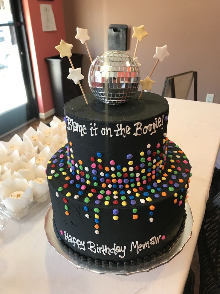 a birthday cake with a disco ball and stars on top is sitting on a table