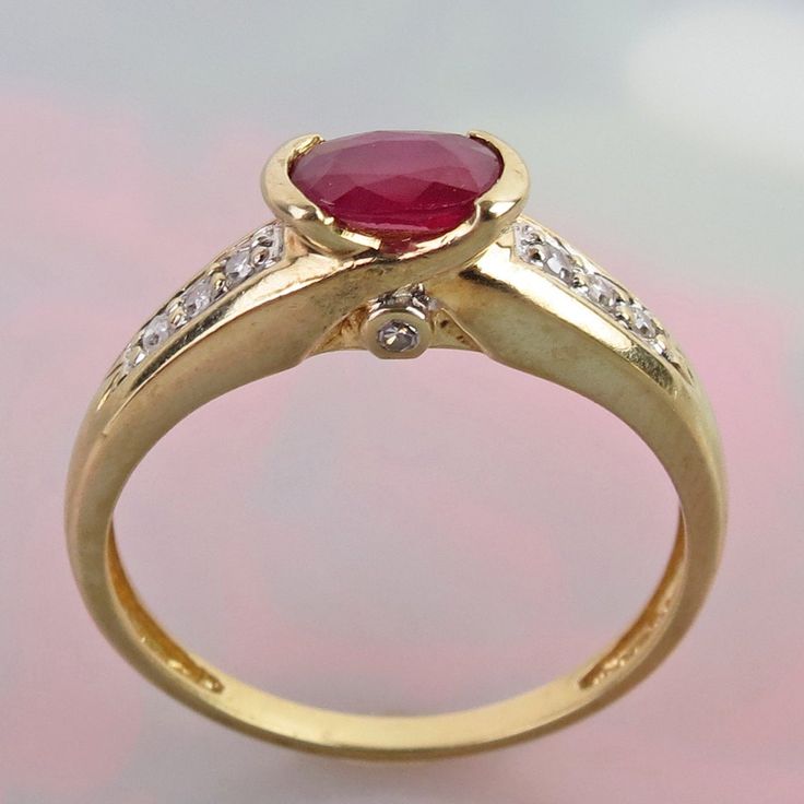 A vibrant natural ruby is centered on this attractive 14k yellow gold diamond ring. The .58 carat oval faceted ruby is of deep raspberry pinkish-red color. It measures 6mm x 4.2mm x 2.9mm and is tightly held by two half-bezels.  Three bright and sparkly 1.5mm diamonds flank the red gem on its shoulders (six total). Each profile side of the ring is also bezel set with a tiny 0.9mm diamond. So, no matter what angle you are looking at the ring you will see a gemstone sparkle. Collectively, the ring Oval Ruby Ring With Diamond Accents For Promise, Gold Oval Ruby Ring With Diamond Accents, Red Oval Diamond Ring With Accents, Red Ruby Ring With Diamond Accents In 14k Gold, Oval Red Diamond Ring With Accents, Oval Ruby Ring With Diamond Accents In 14k Gold, Oval Ruby Birthstone Ring With Diamond Accents, Red Oval Brilliant Cut Birthstone Ring, Oval Ruby Ring Stamped 14k