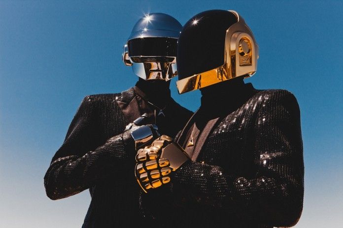 two people in black suits and helmets standing next to each other with their hands on their chests