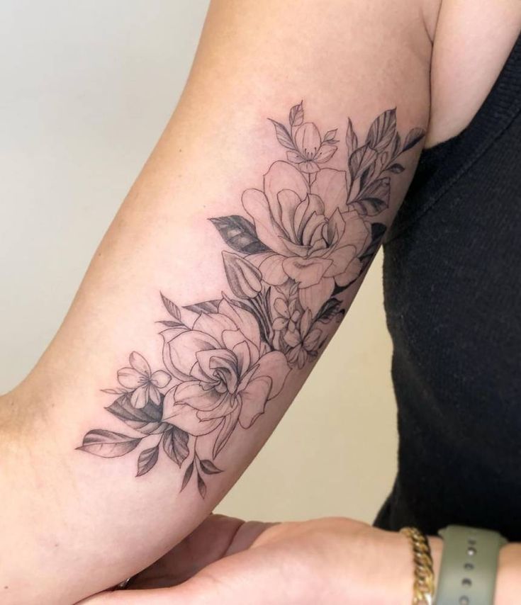 a woman's arm with flowers on it and a small tattoo design in the middle