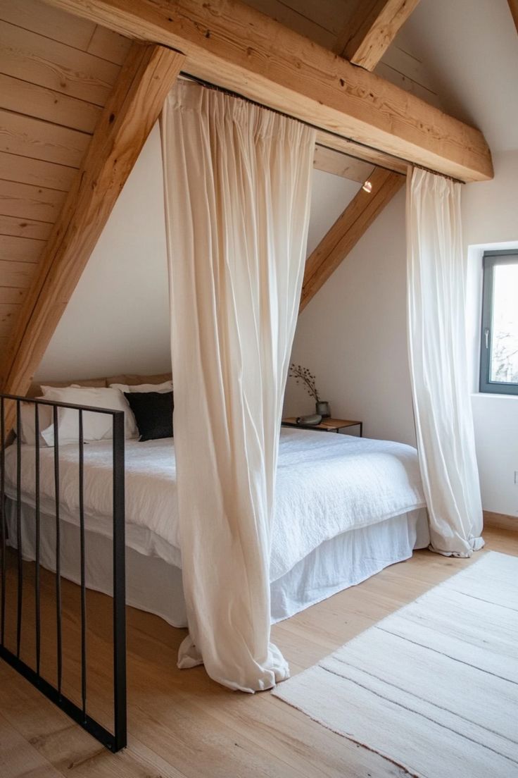 a bed with white sheets and curtains in a lofted room next to a window