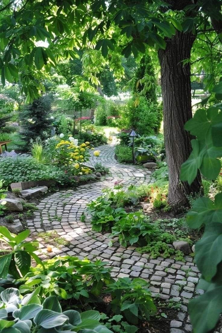 a stone path in the middle of a lush green garden with lots of trees and plants